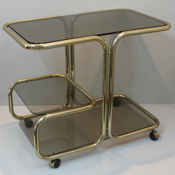 Mesa auxiliar con ruedas o carrito bar. - Metal dorado con cristales tintados
España.