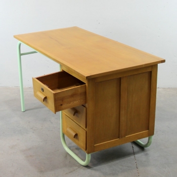 Fabricado en madera de haya y estructura tubular en hierro lacado en verde. Tiene 4 cajones muy grandes. Es una mesa muy estable.