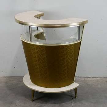 Formica, cristal, madera, latón y aluminio. Tapizado en vinilo dorado.
Tiene un abrebotellas incorporado.