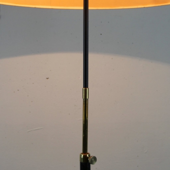 Lámpara de pie realizada en hierro lacado en negro y latón. Pantalla de época. Se puede regular la altura de 168 a 155 cm. Casquillo para bombillas de E27. Algunos arañazos en la base por el paso del tiempo.