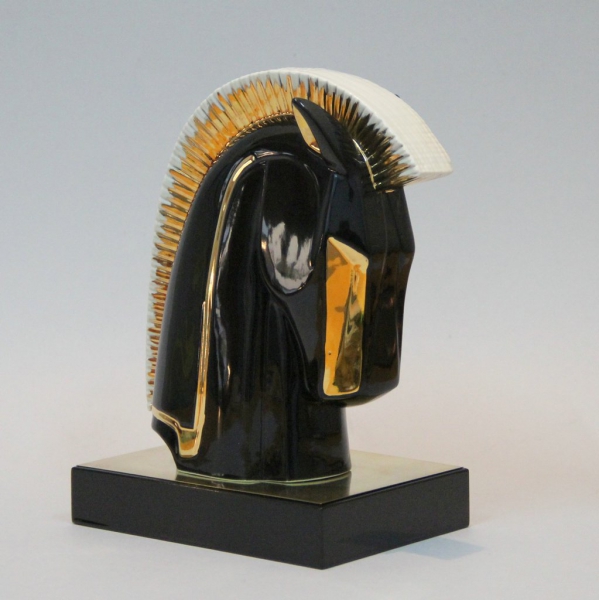 Realizada en porcelana vidriada decorada en negro y dorado, base en latón y madera lacada en negro.
Italia.