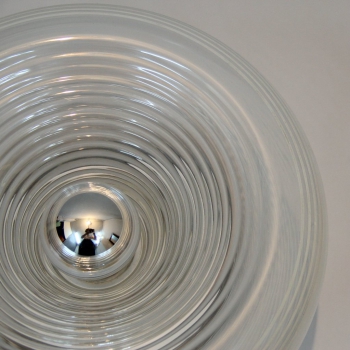Fabricada en metal cromado y cristal con decoracion de lineas circulares en blanco. Bombilla en cromo.
Italia.